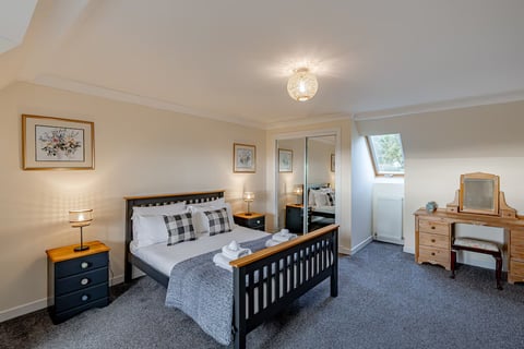 Double bedroom with check cushions and mirrored wardrobes