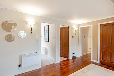 Hallway with wall sconces and warm wood doors