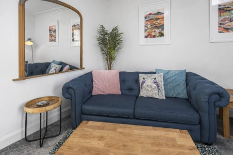 Blue sofa with pink and teal cushions under the arch mirror