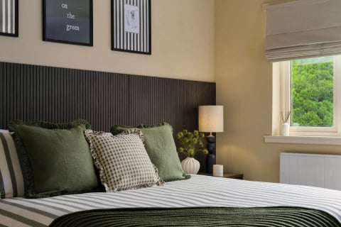 Bed styling with green fringed cushions and lamp