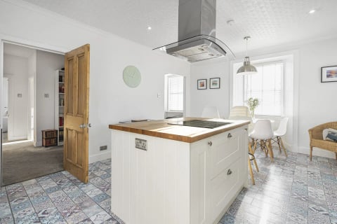 White kitchen island with oak top and pendant lights