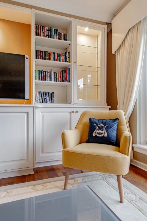 Reading corner with mustard armchair and built-in bookshelves