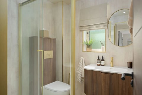 Shower room with gold-trimmed glass and round mirror