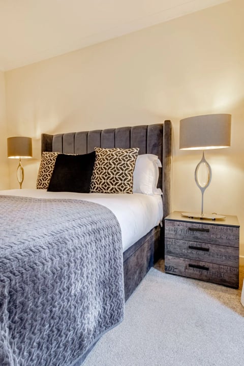 Double bedroom with velvet headboard and grey throw