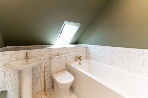 Attic bathroom with bath and brass fittings under the skylight