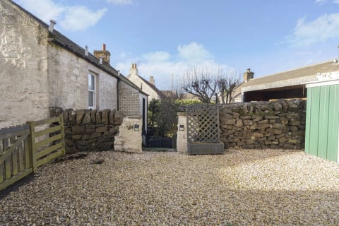 Gravel courtyard with stone walls and trellis gate