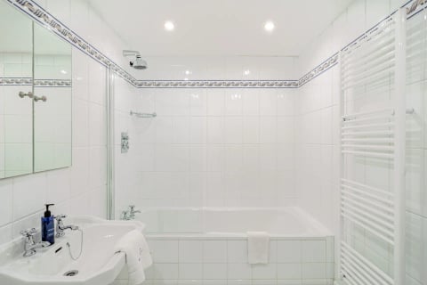 Bathroom with bath, shower over and towel rail