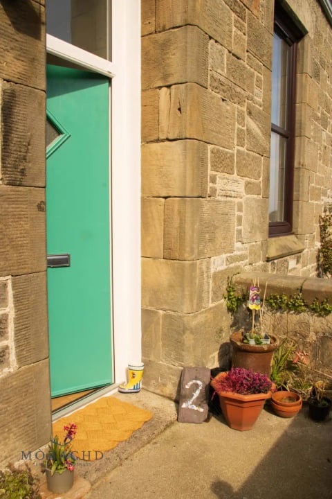 The cottage's mint-green door with potted flowers