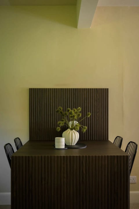 Dining table with vase against the slatted feature wall