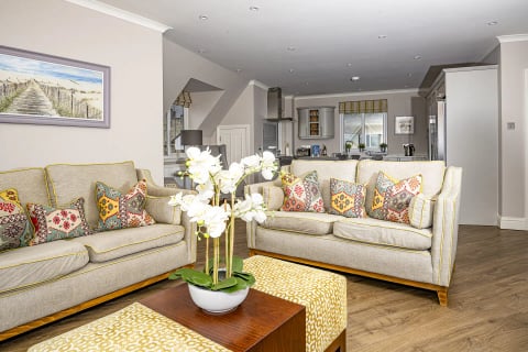 Comfortable lounge with patterned cushions and open-plan kitchen behind