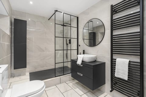 Walk-in shower with black fittings and round mirror