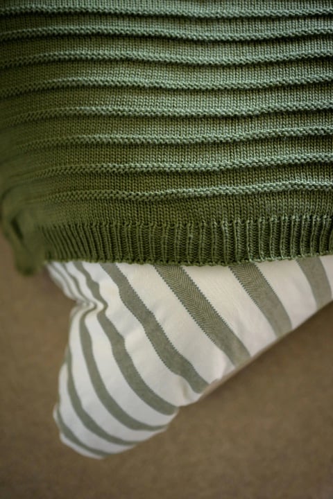 Knitted olive throw over striped linen