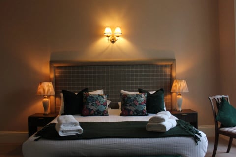King bedroom with tweed headboard and floral cushions
