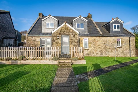 The cottage across its fenced lawn