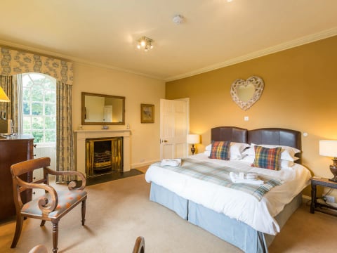 King bedroom with fireplace and tartan cushions