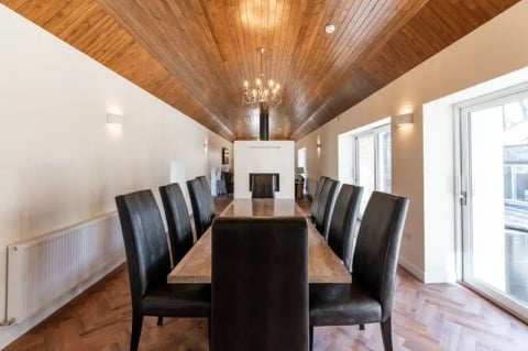 Long dining table beneath the chandelier and timber ceiling