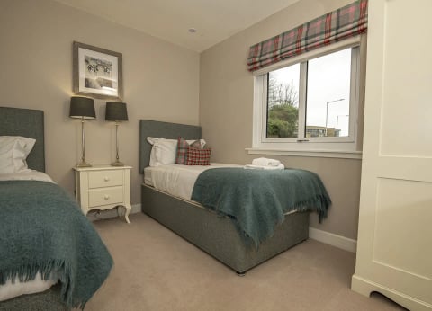 Single bed with green throw and framed print