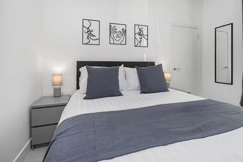Double bed with navy cushions and line-art prints