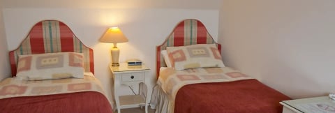 Single bed with plaid headboard and lamp