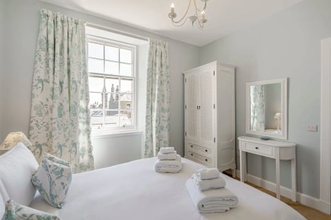 Bright double bedroom with wardrobe, dresser and floral curtains
