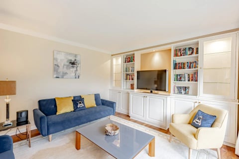 Living room with navy sofas, glass coffee table and TV wall