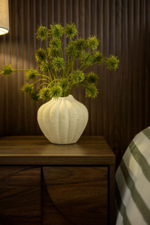 Dried stems in a ribbed vase against the panelling