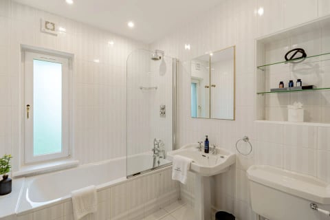 Bathroom with shower screen and gold-trimmed glass shelves