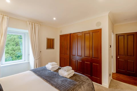Double bedroom with dark throw and fitted wardrobes