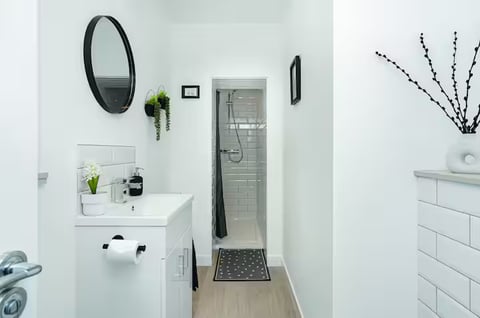 Shower room with round mirror, vanity basin and rainfall shower