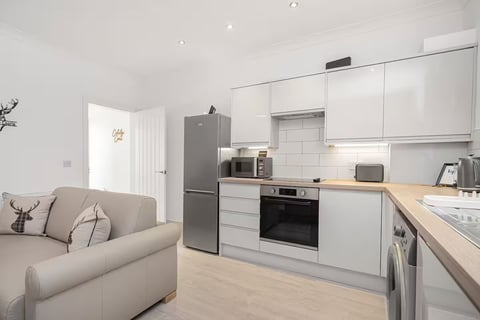 Compact fitted kitchen with oven and smart speaker