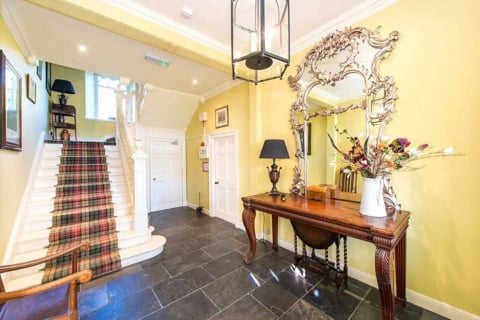 Entrance hall with tartan-carpeted staircase and ornate mirror