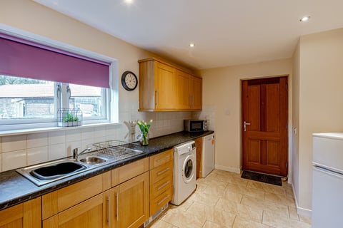 Oak kitchen with washing machine and black worktops
