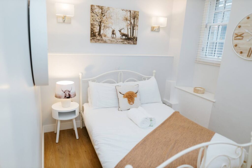 Cozy bedroom with white decor, animal-themed art, and soft lighting, creating a serene and inviting atmosphere.