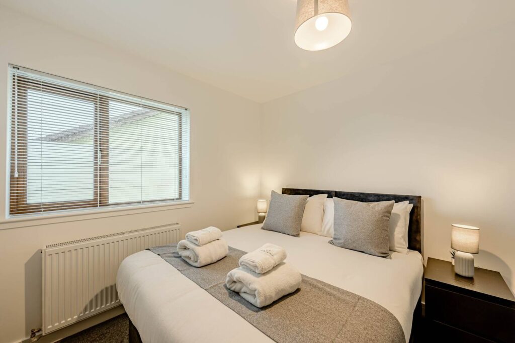 Modern bedroom with cozy double bed, soft bedding, and warm lighting, creating a relaxing atmosphere.