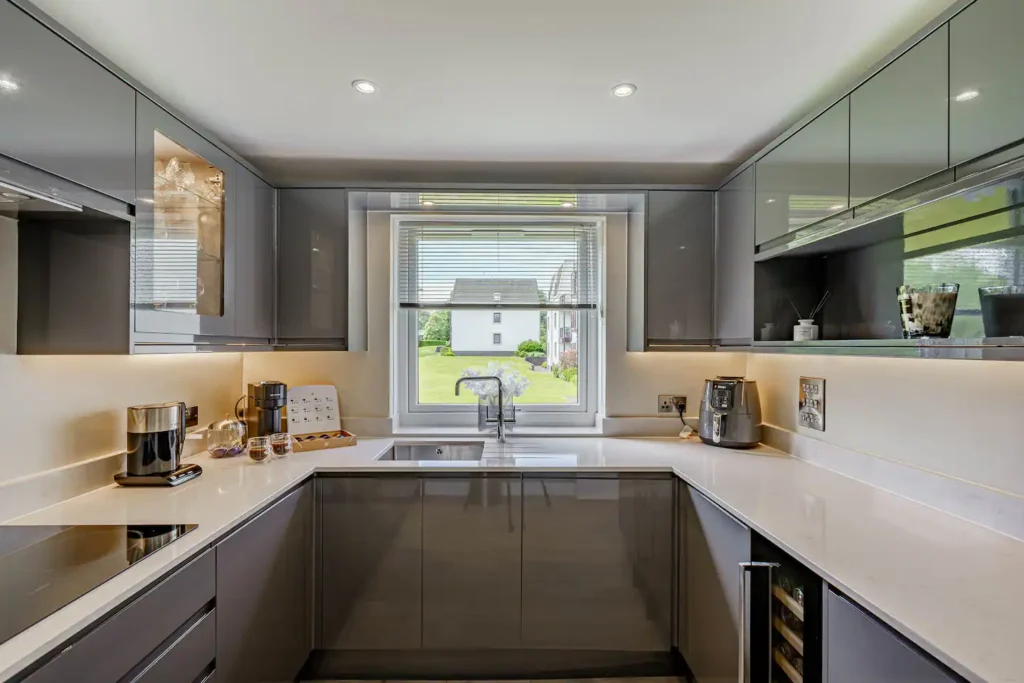 Modern kitchen with sleek gray cabinets, a large window view, and stainless appliances.