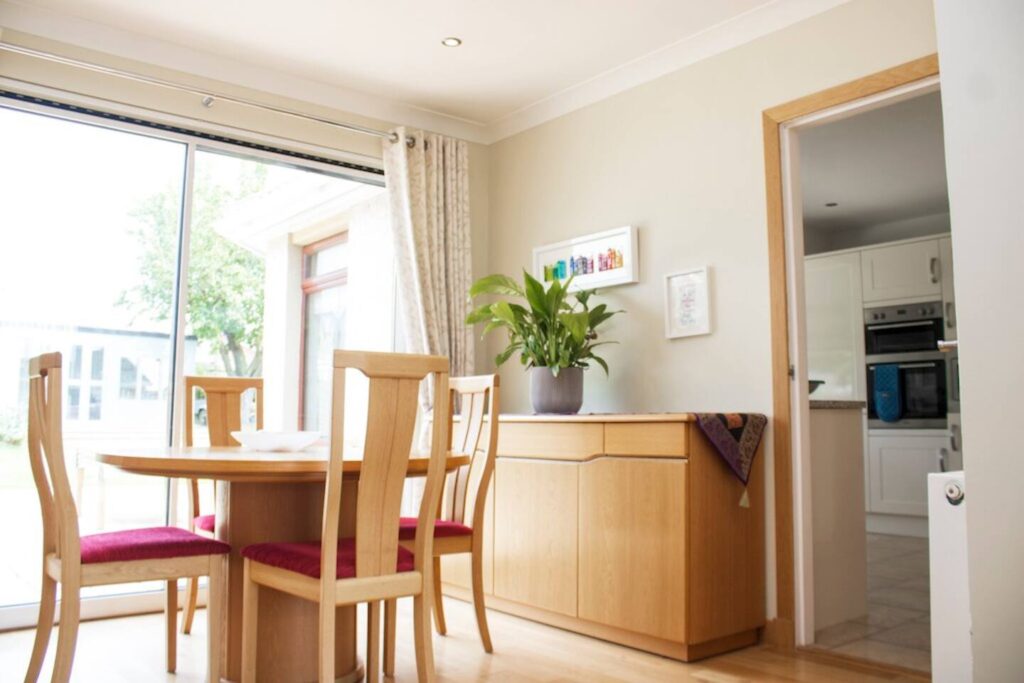 Bright dining room with wooden furniture, sliding glass doors, and a potted plant for a cozy, natural feel.