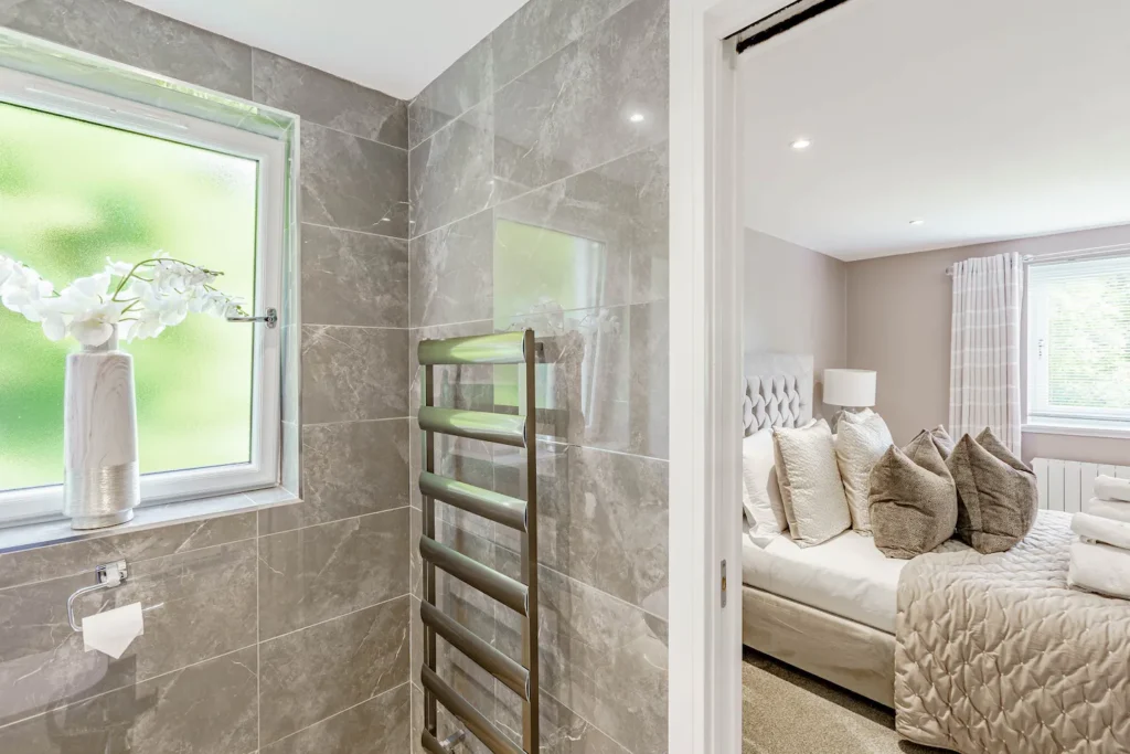 Luxury bathroom view into cozy bedroom with plush pillows and elegant decor.