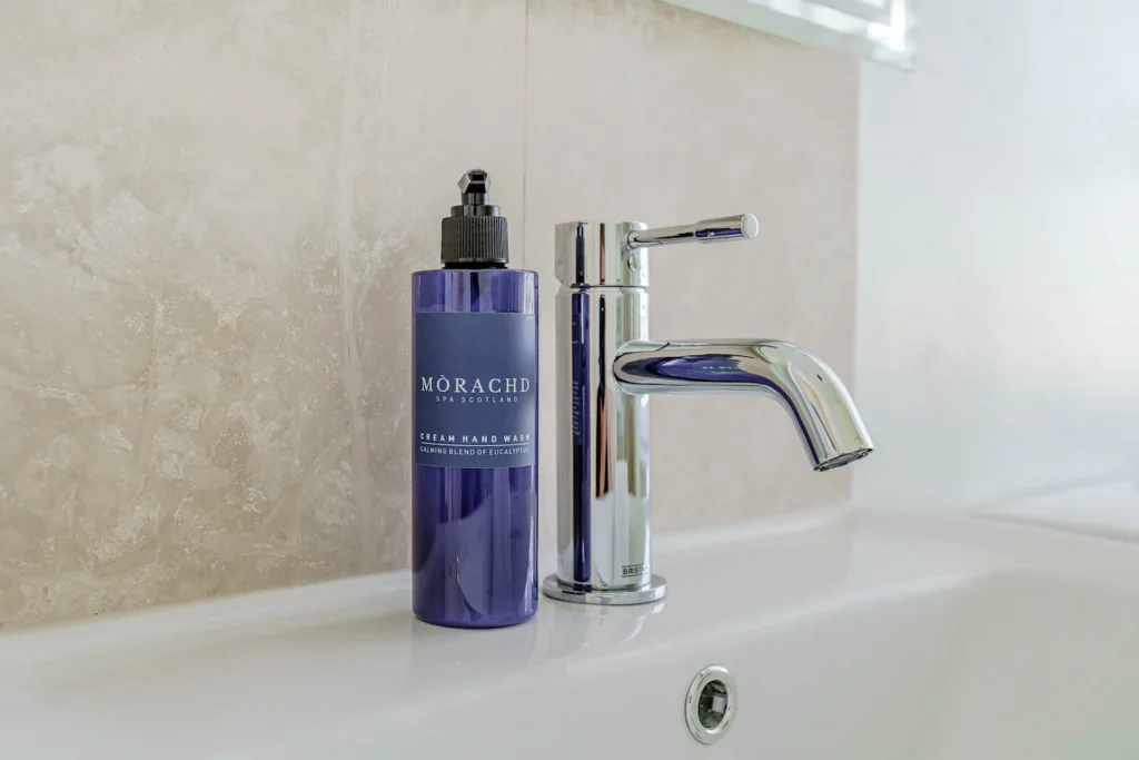 Luxury hand wash and modern chrome faucet on a white bathroom sink.