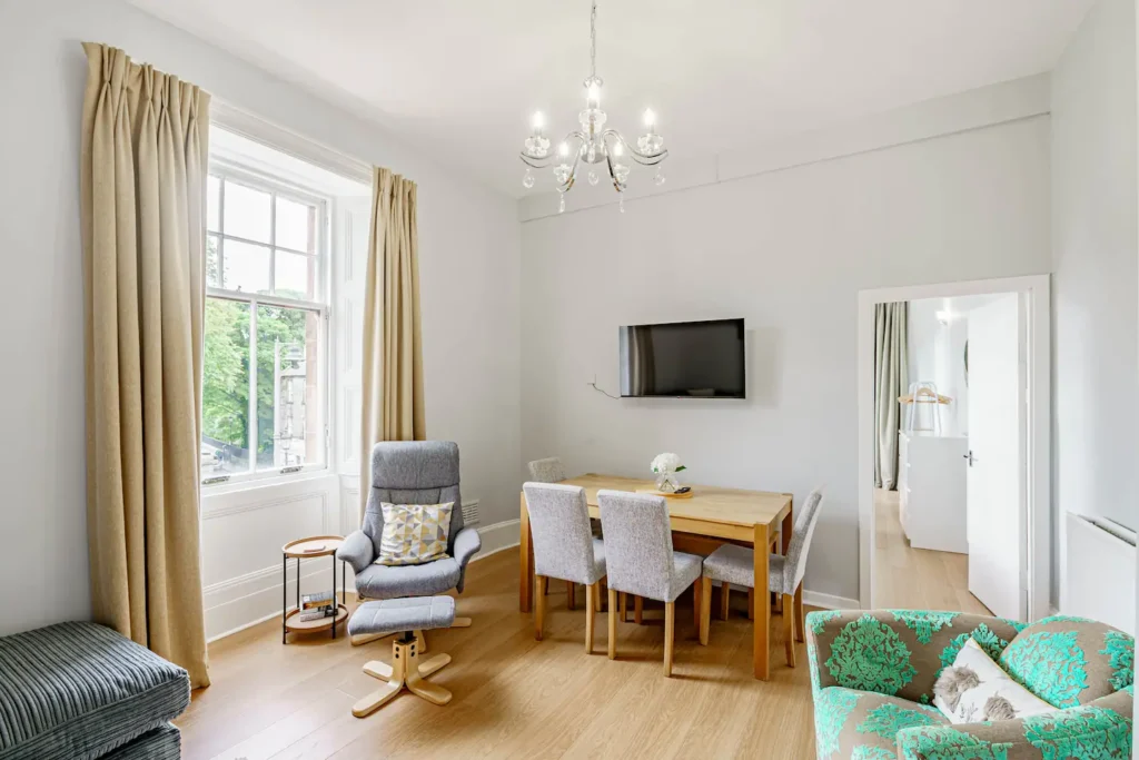 Bright living room with modern decor, cozy seating, dining table, and wall-mounted TV.