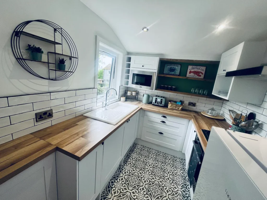 Modern kitchen with white cabinets, wooden countertops, patterned floor tiles, and stylish open shelving.