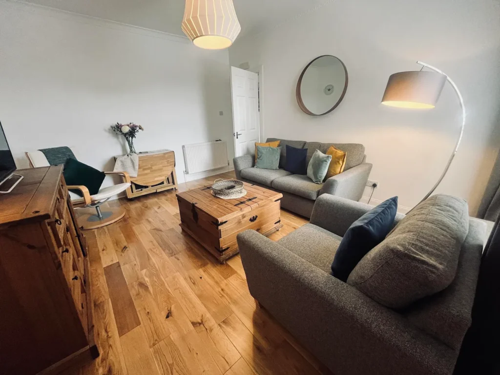 Cozy living room with gray sofas, wooden furniture, floor lamp, and modern decor.