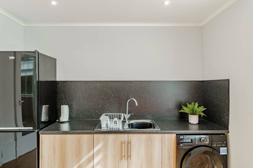 Modern kitchen with black appliances, wooden cabinets, and a sink, complete with a plant on the countertop.