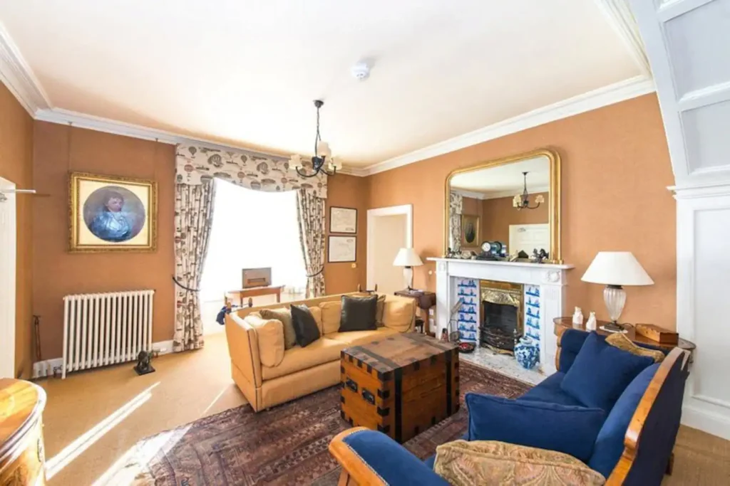 Elegant living room with vintage decor, blue sofas, and a fireplace.