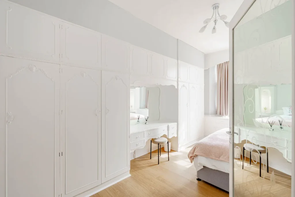 Bright, elegant bedroom with white vintage furniture, large closet, and a cozy bed.