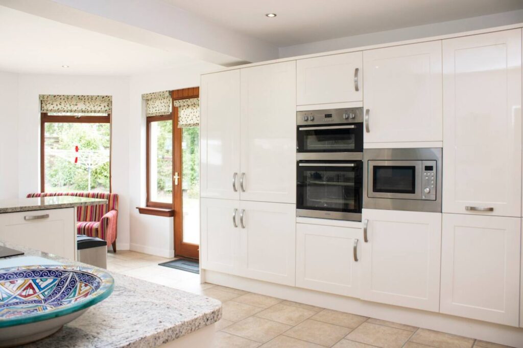 Modern kitchen with white cabinets, built-in appliances, granite countertops, and large windows for natural light.