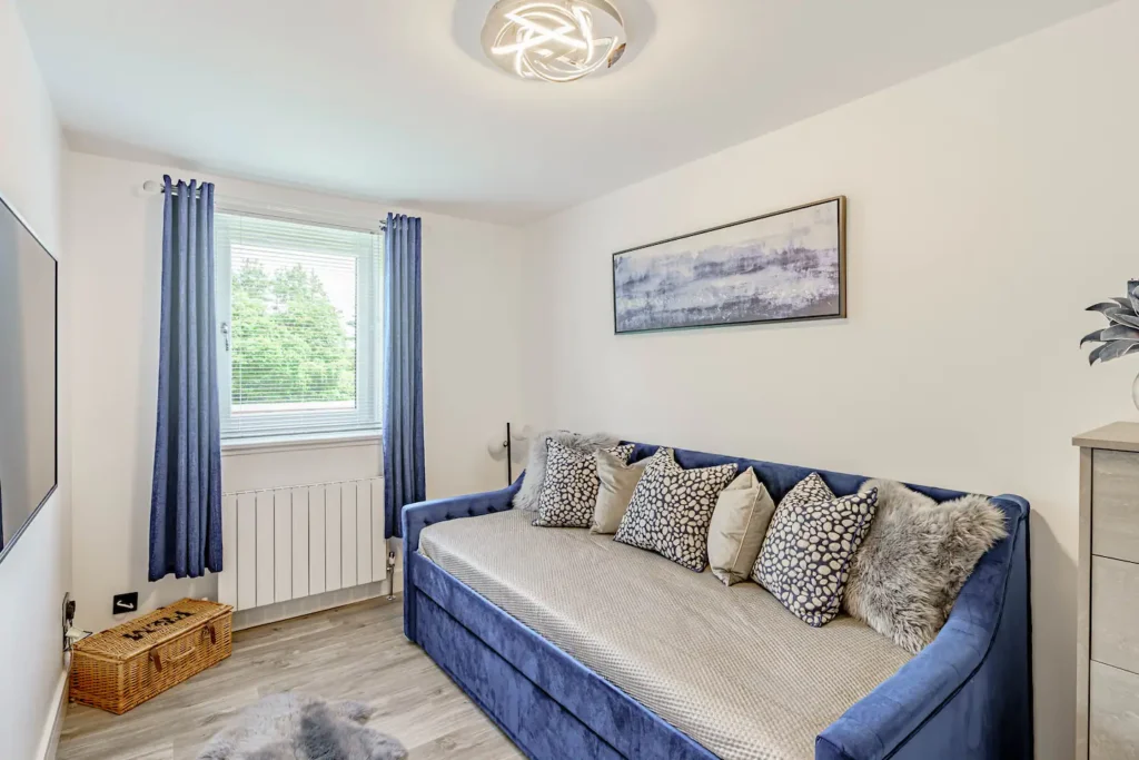 Cozy, modern living room with blue sofa, decorative pillows, and window view. Bright, stylish decor.