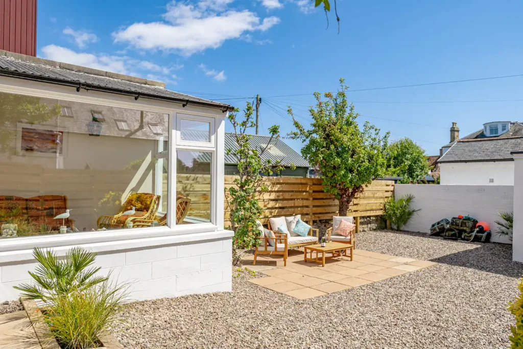 Sunny backyard with patio furniture and garden, perfect for outdoor relaxation.