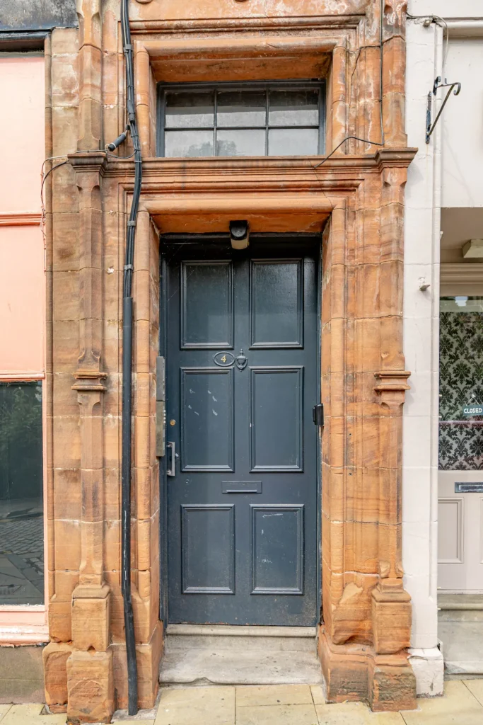 Elegant dark blue door set in rustic brick building facade.