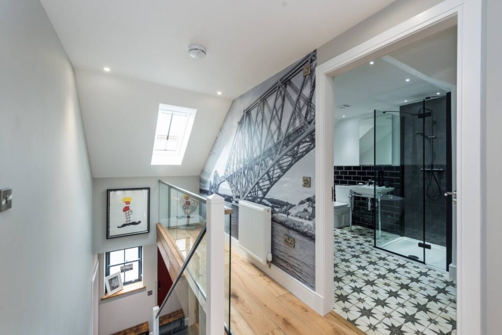 Modern hallway with bridge mural, skylight, and stylish bathroom featuring patterned tiles and glass shower enclosure.