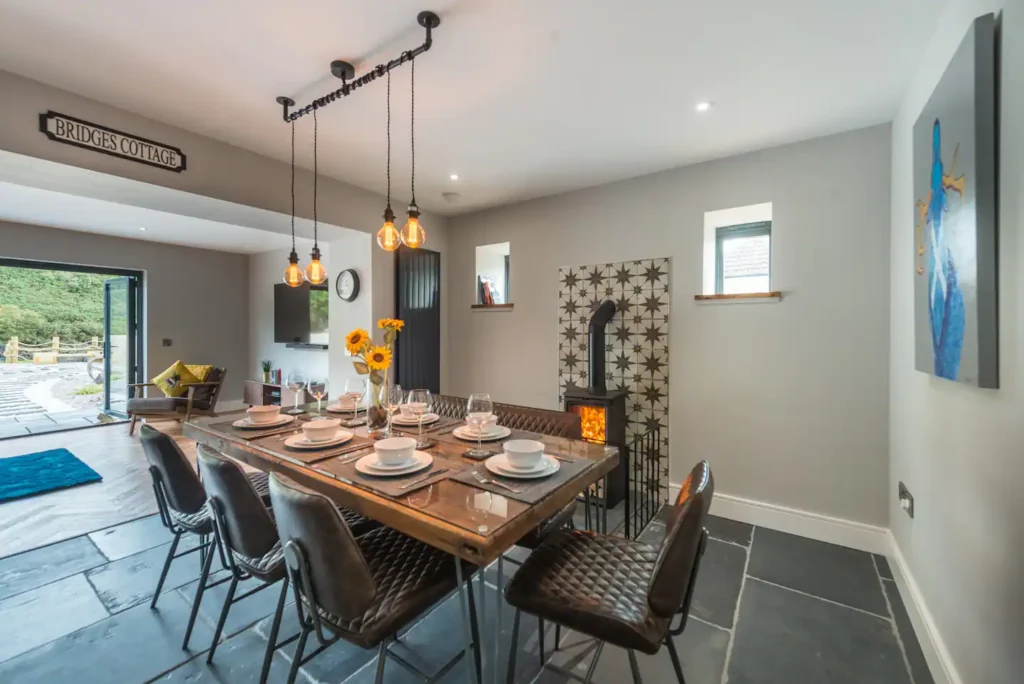 Modern cottage dining room with rustic decor, sunflowers, and wood-burning stove. Cozy interior design.